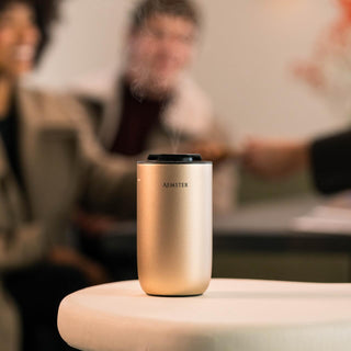 Gold aroma diffuser with steam on a blurred background of people