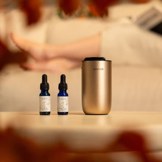 Two small bottles and a gold aroma diffuser on a table with a blurred background
