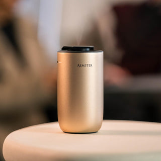 Gold aroma diffuser with 'Aemster' branding on a blurred background